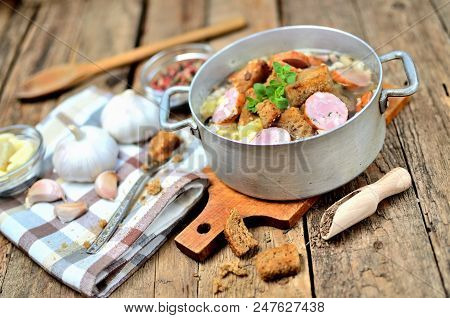 Garlic Soup In An Old Saucepan, Fresh Garlic Bulbs, Cloves, Colored Pepper, Wooden Spoon, Croutons A