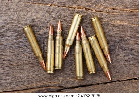 Fire Arm Or Rifle Bullet Cartridges On A Old Wooden Table. High Resolution Photo.
