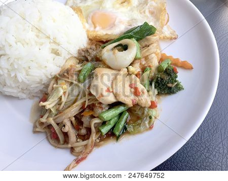 Fried Spicy Fried Seafood With Basil Leaves And Mixed Vegetable And Fried Egg On Jasmine Rice In Whi