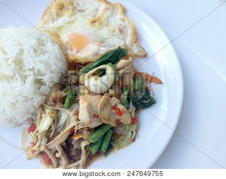 Fried Spicy Fried Seafood With Basil Leaves And Mixed Vegetable And Fried Egg On Jasmine Rice In Whi