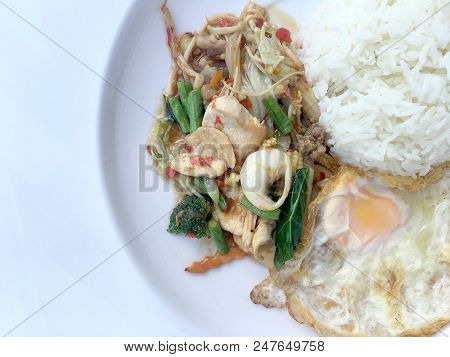 Fried Spicy Fried Seafood With Basil Leaves And Mixed Vegetable And Fried Egg On Jasmine Rice In Whi
