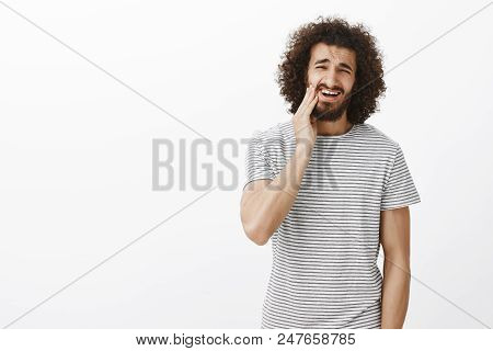 Portrait Of Displeased Bothered Handsome Eastern Male Student With Afro Hairstyle In Striped T-shirt