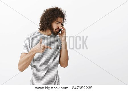 Studio Shot Of Bossy Handsome Hispanic Businessman With Beard And Afro Hairstyle, Turning Right Whil