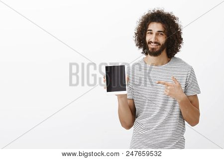 Indoor Shot Of Pleased Attractive Male Sportsman With Beard And Afro Hairstyle, Showing Digital Tabl