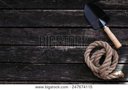 Shovel And Rope On Old Wooden Table. Archaeologist Or Treasure Hunter Table With Copy Space.
