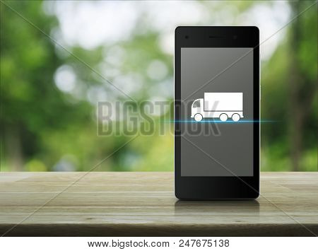 Truck Flat Icon On Modern Smart Phone Screen On Wooden Table Over Blur Green Tree In Park, Business 
