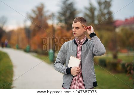 A Cute Student Writes Down His Thoughts In His Notebool Using A Pensil.