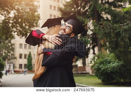 Pair Of Students Hugging On Their Graduation Day At University, Having Fun And Saying Good Bye To Fr