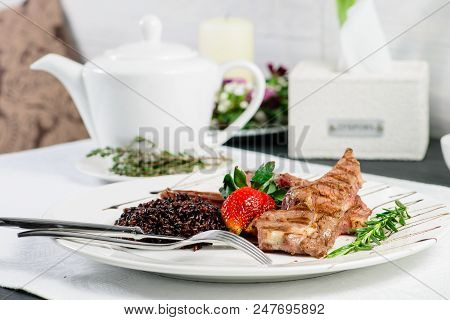 Appetizing Dish In A Restaurant: Juicy Mutton Ribs Of Medium Rare With Brown Rice, Strawberry And Sa