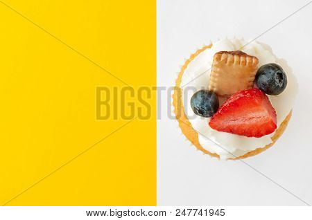 Cupcake With Cream, Strawberry, Blueberry And Cookie On Yellow White Background. Looks Like A Flag. 