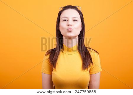 Pretty Girl Making Kiss To The Camera On Yellow Background