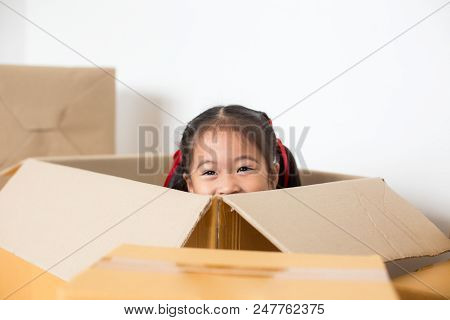 Asian Girl Playing In The Box At Home. Kid Sitting Inside Box With Attractive Smiling.