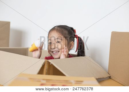 Asian Girl Playing In The Box At Home. Kid Sitting Inside Box With Attractive Smiling.
