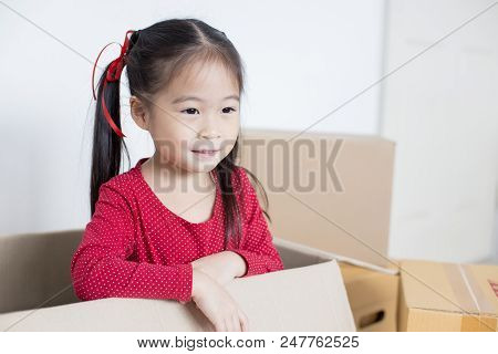 Asian Girl Playing In The Box At Home. Kid Sitting Inside Box With Attractive Smiling.