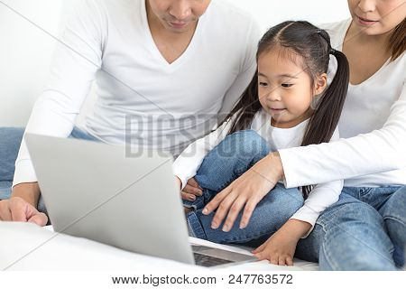 Attractive Little Girl Using Laptop With Mom And Dad Together. Girl Learning To Use Laptop. Happy Fa