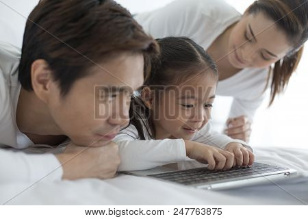 Attractive Little Girl Using Laptop With Mom And Dad Together. Girl Learning To Use Laptop. Happy Fa