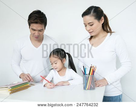 Attractive Little Girl Writing Book. Mom And Dad Teaching Her At Home. People Lifestyle, Education C