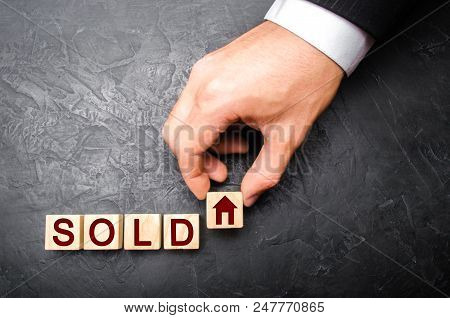 Realtor's Hand Puts A Cube With A Picture Of The House To The Word Sold. Concept Of Selling A House,