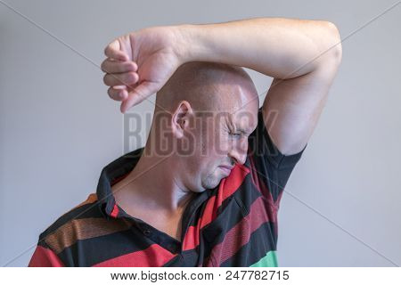 Bald Man, Smelling Sniffing His Armpit, Something Stinks Bad. On Grey Background.