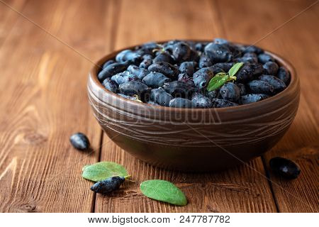 Honeysuckle Berries Or Lonicera Caerulea In Ceramic Bowl On Wooden Background