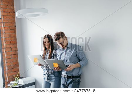 Portrait Of Two Heterosexual Colleagues In Office Interior, Sharing Useful Information Using Laptop 