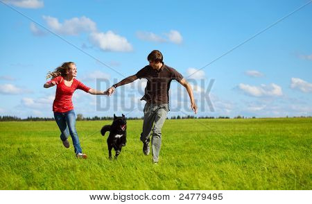 Unge lykkelig familie kører med hund på en grøn eng