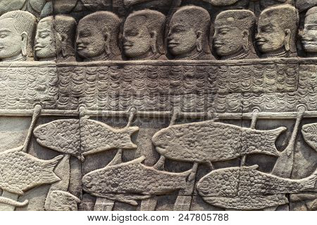 Ancient Temple Stone Carved Bas-relief In Angkor Wat. People In Boat And Fishes Bas-relief Closeup. 