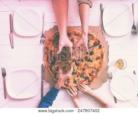 family clank glasses together having a dinner with pizza
