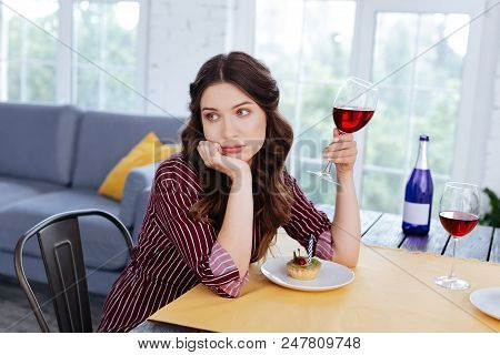 Nice Hairstyle. Appealing Stressed Woman With Nice Hairstyle Drinking Glass Of Red Wine On Her Own