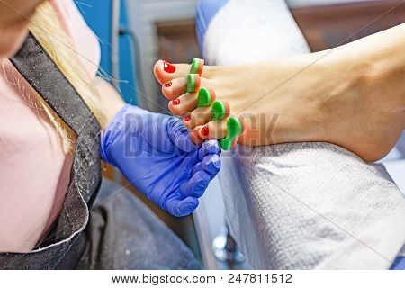 Master During A Pedicure. The Process Of Professional Pedicures. The Wizard In The Mask Causes The G