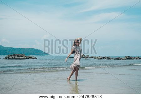 Handsome Girl On The Beach Background. Portrait Of A Woman In White Clothes On The Sea