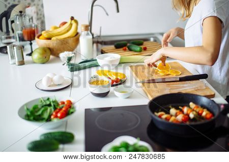 Cropped Shot Of Unrecognizable Woman Cooking Lunch In The Modern White Kitchen. She Placed Colorful 