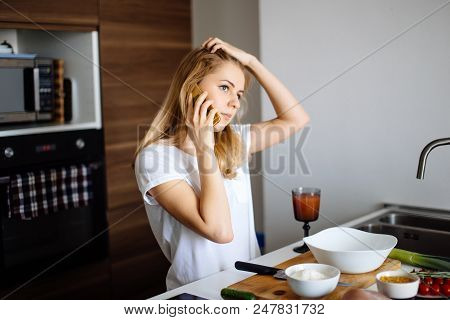 Smiling Caucasian Woman Making Healthy Meal And Reading Message At Phone In The Domestic Kitchen.