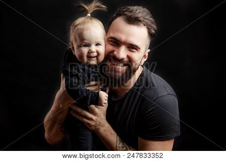 Happy Father And Infant Daughter Posing With Different Grimaces At Studio Black Background Witj Copy