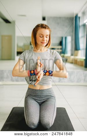 Woman Practicing Yoga Lesson In Empty Hall, Sitting On Knees In Vajrasana Pose With Closed Eyes, Med