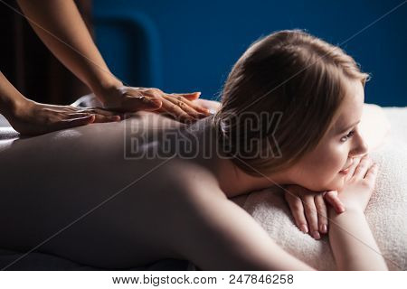 Cropped View Of Massage Therapist Hands Hands Massaging The Back, Lying On The Belly Of A Woman