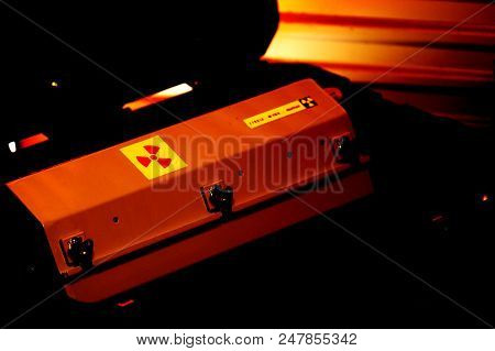 Box Shaped Metal Container With Radiation Warning In A Military Grade Transport Box Under Red Light