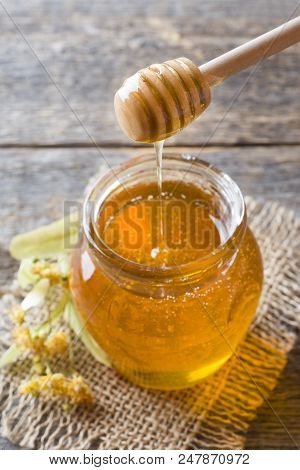 Glass Jar Of Honey, Linden Flowers On Wooden Background