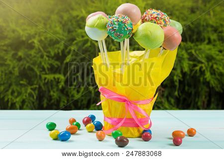 A Lot Of Colored Pop Cakes In A Glass On Turquoise Boards, In The Open Air, Against A Background Of 
