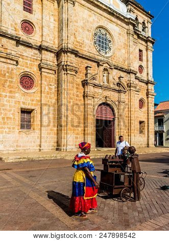 Cartagena, Colombia. March 2018. A View Of A Traditionally Dressed Woman Outside The Cathedral San P
