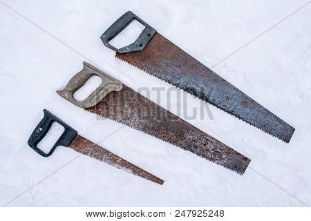 Set Of Old Rusty Crosscut Saws On Snow Background