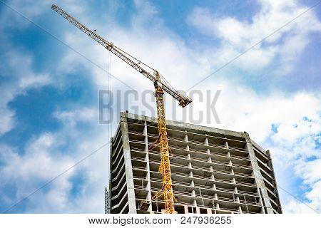 Skyscraper Construction. Tower Crane Over Construction Building On Sky Background
