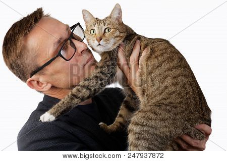 A Man In Glasses Holds A Cat In His Hands And Looks At Her Attentively. The Cat Looks Away Warily. I