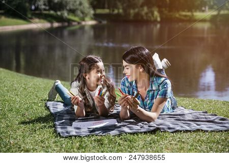 Beautiful Mother And Daighter Are Lying Together On Blanket And Looking At Each Other. They Are Smil