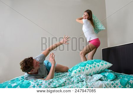 Young Couple Having Fun In Bedroom With Pillow Fight.