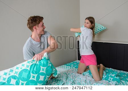 Young Couple Having Fun In Bedroom With Pillow Fight.