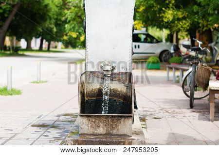 Flowing Artesian Well, And A Decorative Spigot Installed On It. Selective Focus. The Blurry Contours