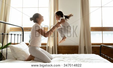 Overjoyed Young Mum And Little Daughter Play At Home