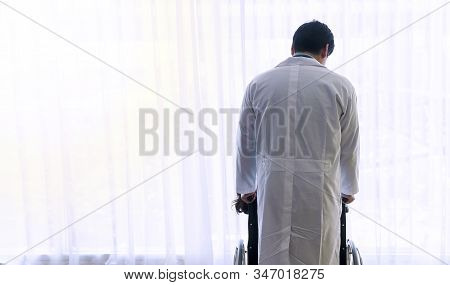 Back Of Young Doctor Wear White Coat Uniform Take Care Standing Push Patient Wheelchair While Lookin