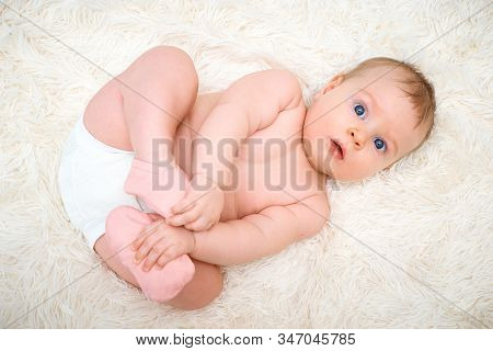 A Small Child Is Lying On His Back And Holding On To The Legs
